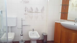 A bathroom with a toilet, bidet, sink, and mirror. - The ideal starting point for a peaceful and relaxing vacation. (Tirano)