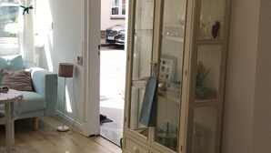 Une pièce avec un canapé bleu clair, une table blanche, un lampadaire et un meuble avec des portes en verre.