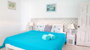 A bed with a blue bedspread, star-patterned pillows, and two bedside lamps.