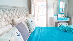 A bedroom with a bed, a dresser, a mirror, and a view of the outside.
