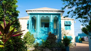 A house with a distinctive blue facade, a tiled roof, and a small porch with a lattice design.
