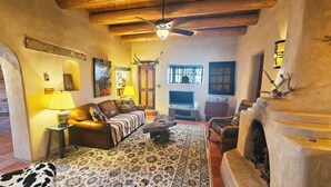 Una sala de estar acogedora con chimenea, un sofá, un televisor y un tapete estampado.