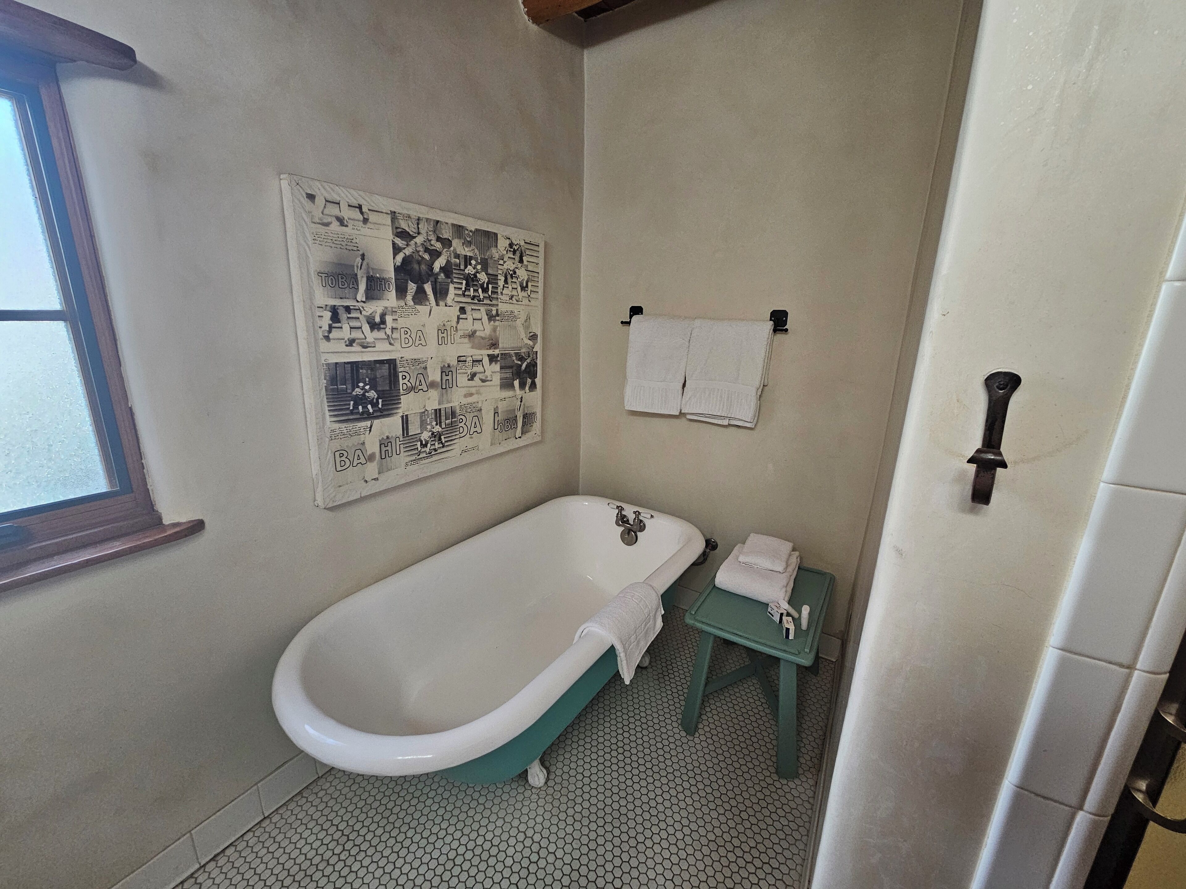 Ein Badezimmer mit einer Badewanne, einem kleinen Tisch mit einem Handtuch und einem Wandhandtuchhalter.