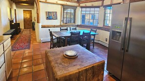 Una cocina rústica con vigas de madera, una mesa de comedor, sillas, un refrigerador y una ventana con vistas.