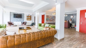 A spacious living area with a leather sofa, a green sofa, and a red door. - İznik Otel (Iznik)