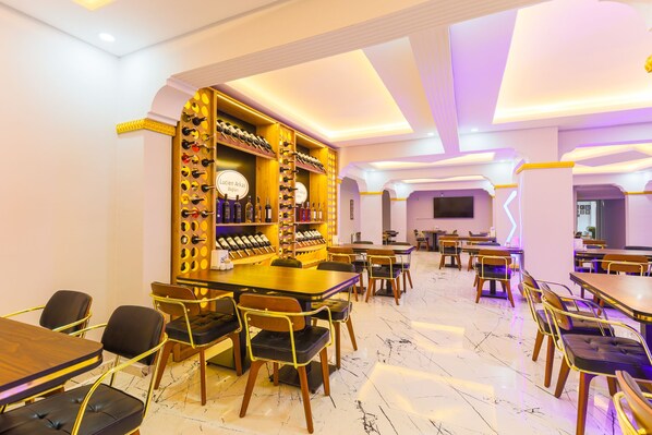 A restaurant with marble flooring, wooden tables and chairs, and a wine display.