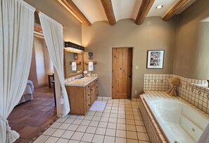 A bathroom with a wooden vanity, a large bathtub, and a shower area. - Sweeping panoramic mountain views, expansive adobe privacy wall system (Arroyo Seco)