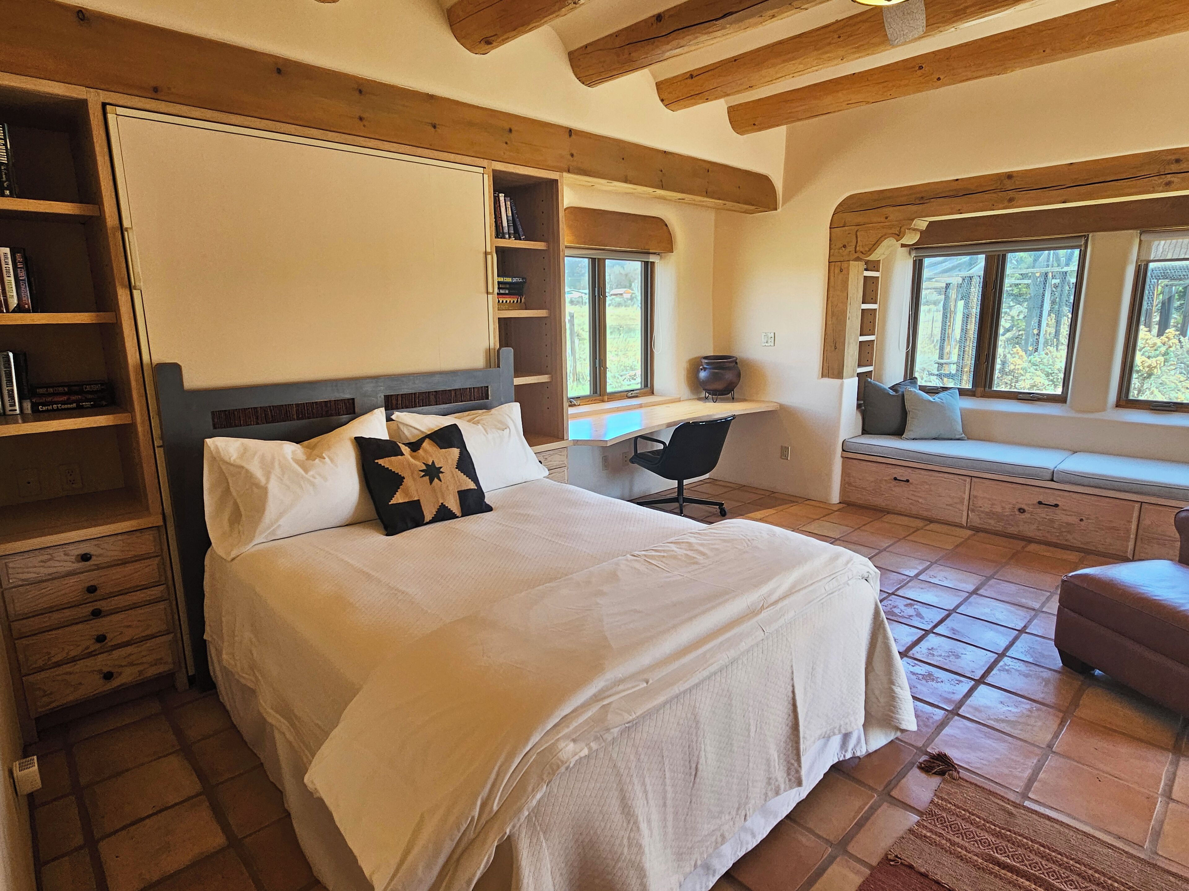 Een slaapkamer met een groot bed, een bureau en een vensterbank.