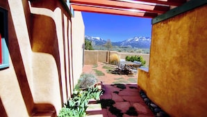 A patio with a view of mountains, a table and chairs, and a pergola structure. - Sweeping panoramic mountain views, expansive adobe privacy wall system (Arroyo Seco)