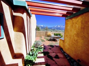 A patio with a view of mountains, a table and chairs, and a pergola structure. - Sweeping panoramic mountain views, expansive adobe privacy wall system (Arroyo Seco)