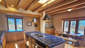 Una cuina àmplia amb armaris de fusta, una illa gran amb una aixeta i una zona de menjador amb taula i cadires de fusta.