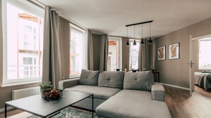 Una sala de estar moderna con un sofá seccional gris, una mesa de centro y un ventanal con cortinas.