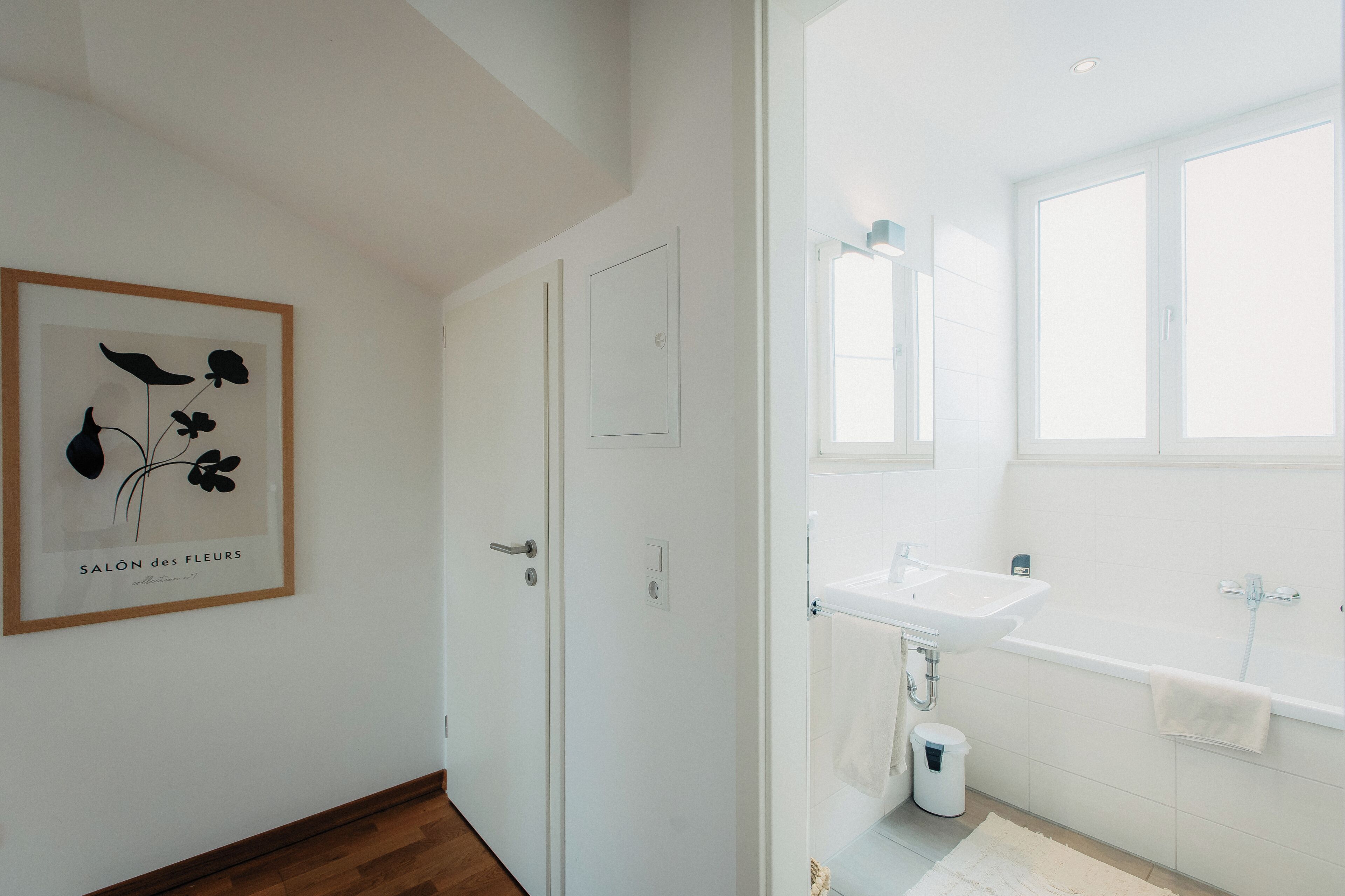 Une salle de bain moderne avec un lavabo blanc, une baignoire et de grandes fenêtres.