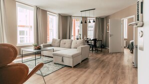 Una sala de estar moderna con un sofá seccional color beige, una mesa de centro y un comedor con mesa y sillas.
