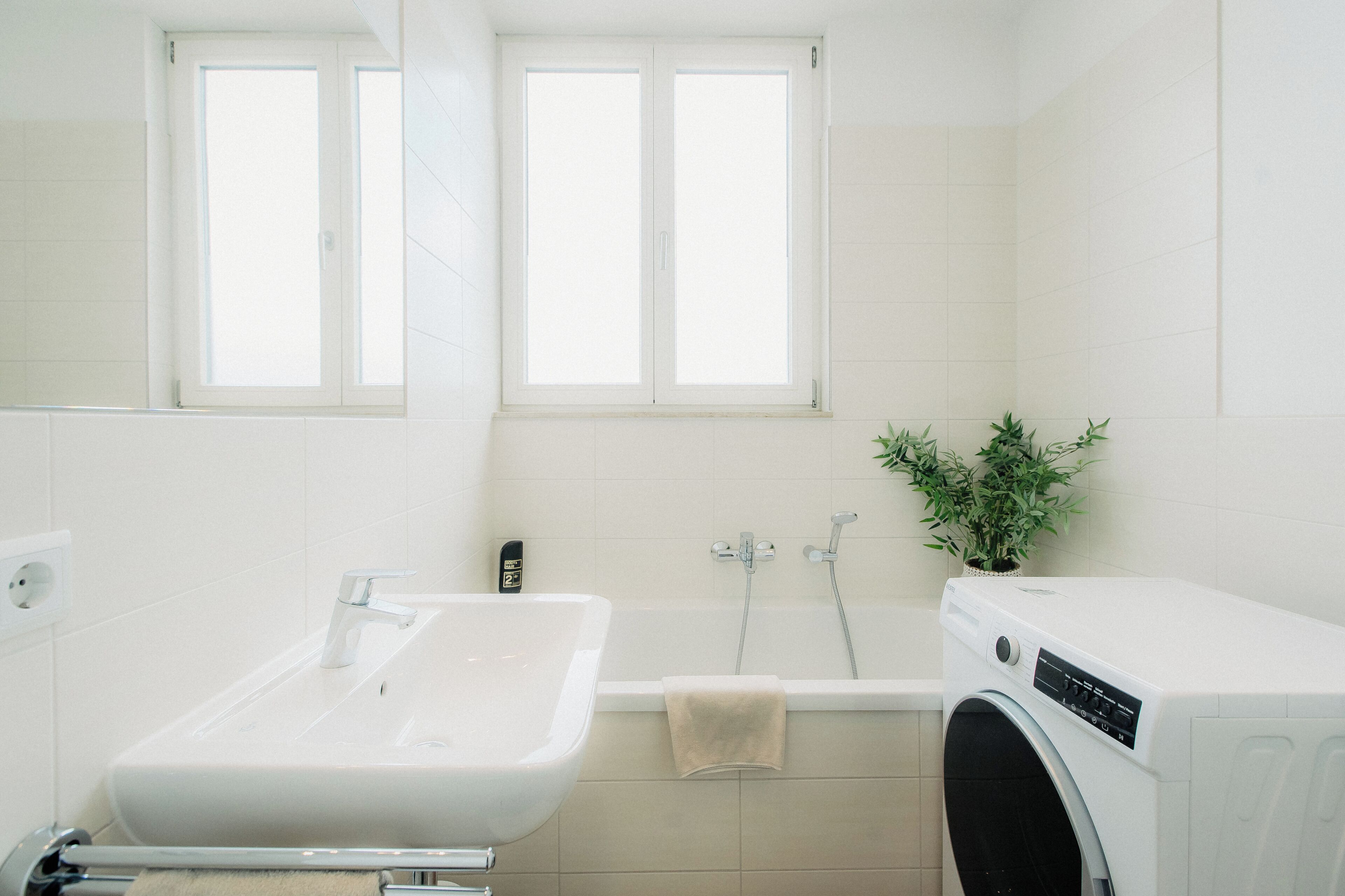 A bathroom with a sink, bathtub, and a washing machine.