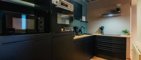A compact kitchen with a microwave, oven, and built-in cabinets.
