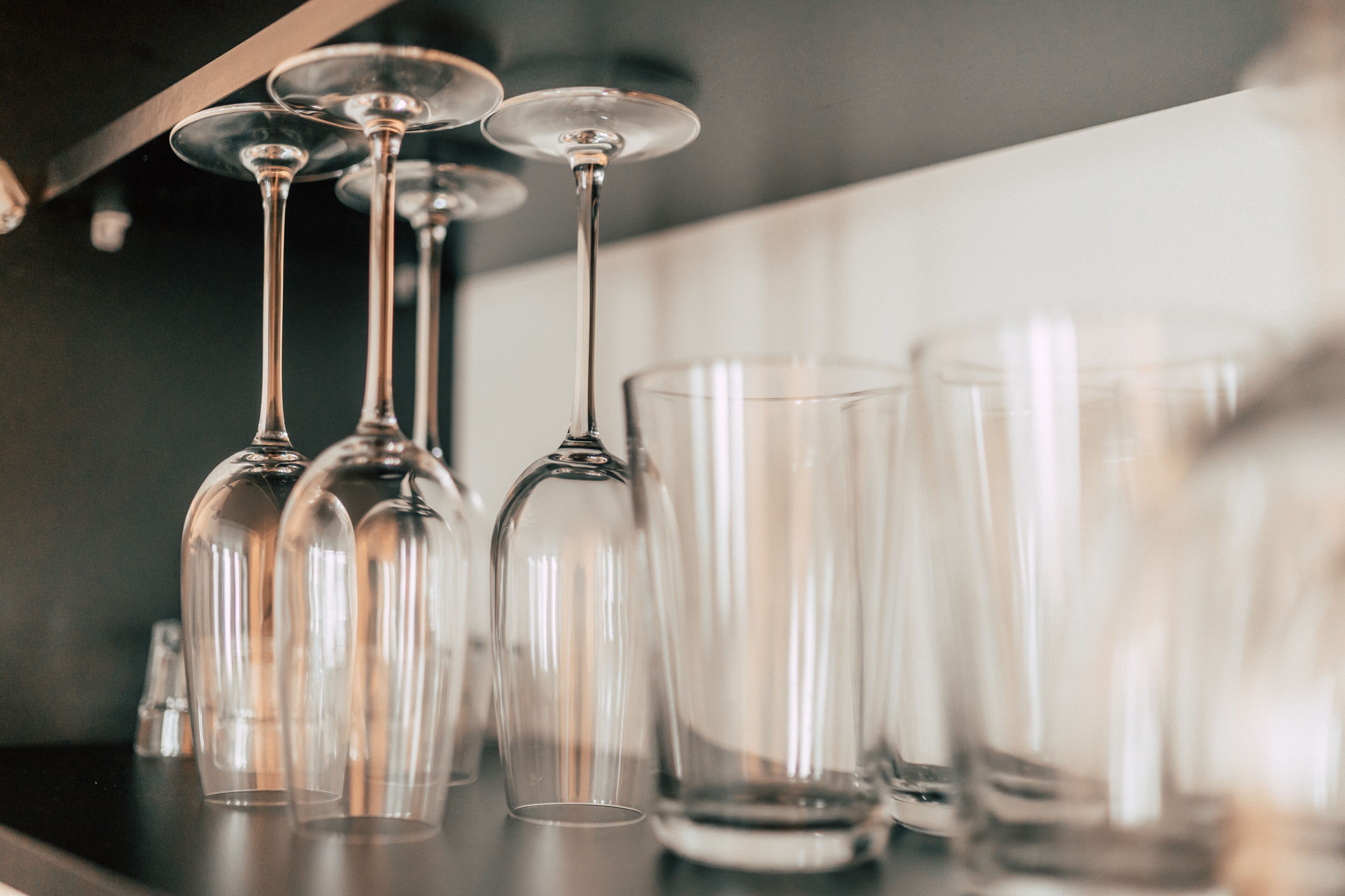 A row of clear wine glasses on a shelf.