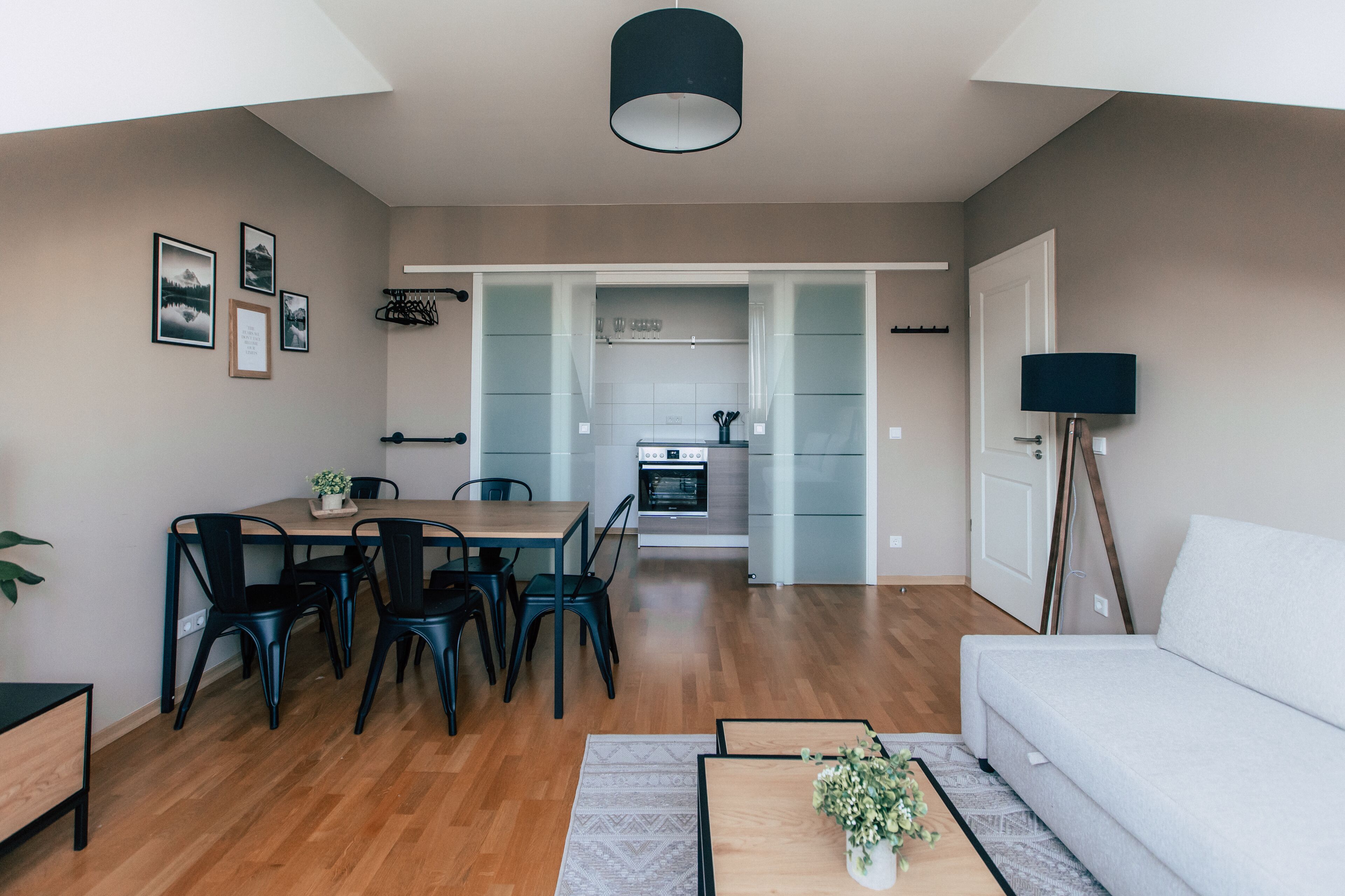 A modern living room with a dining area, a sofa, and a kitchen in the background.