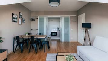A modern living room with a dining area, a sofa, and a kitchen in the background.