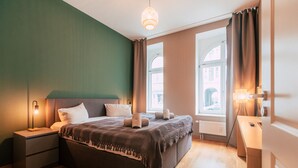 Un dormitorio moderno con una cama grande, lámparas de noche y vistas de la ciudad a través de amplias ventanas.