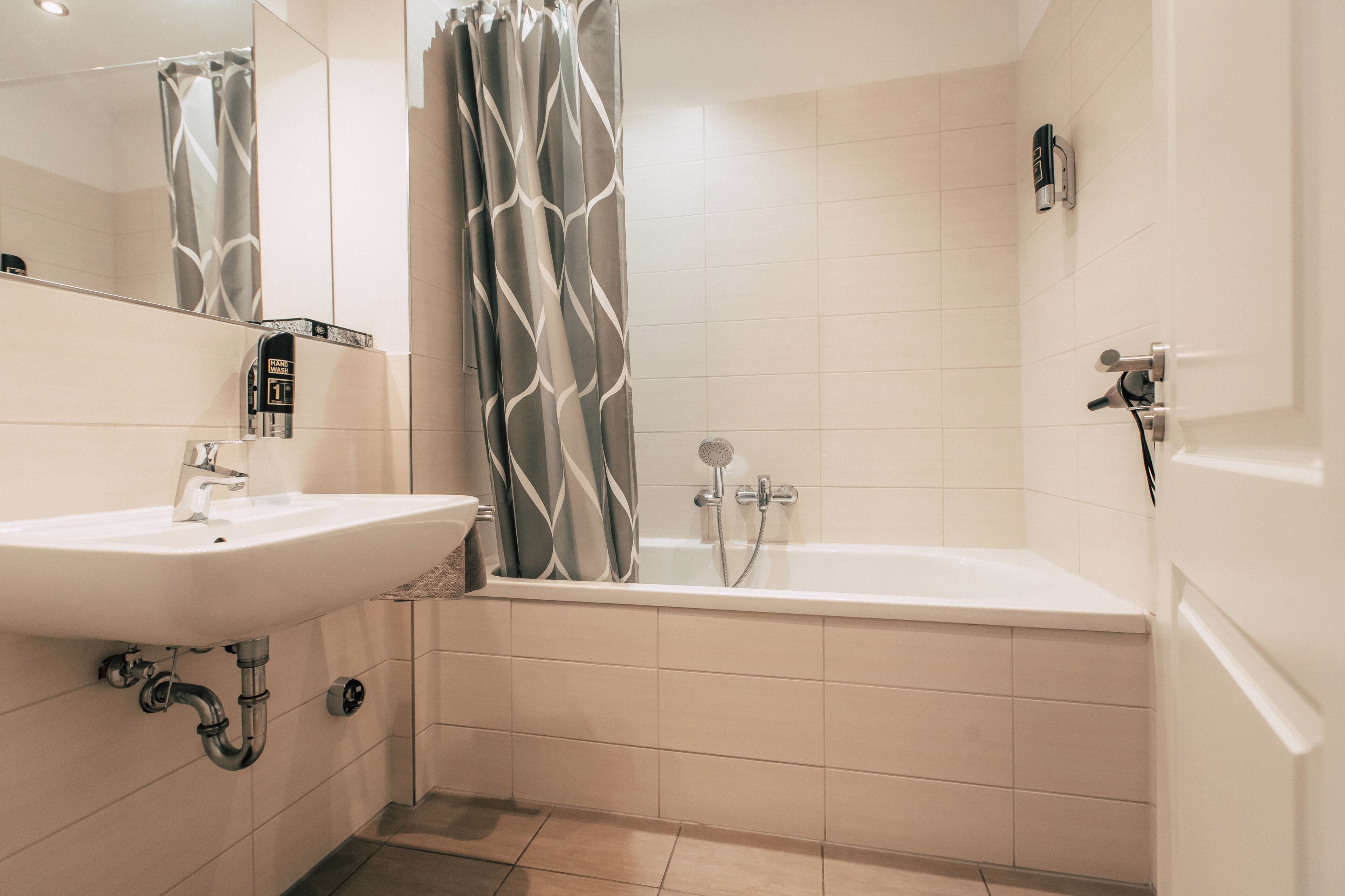 Een badkamer met een wit wastafelmeubel, een bad en een douche.