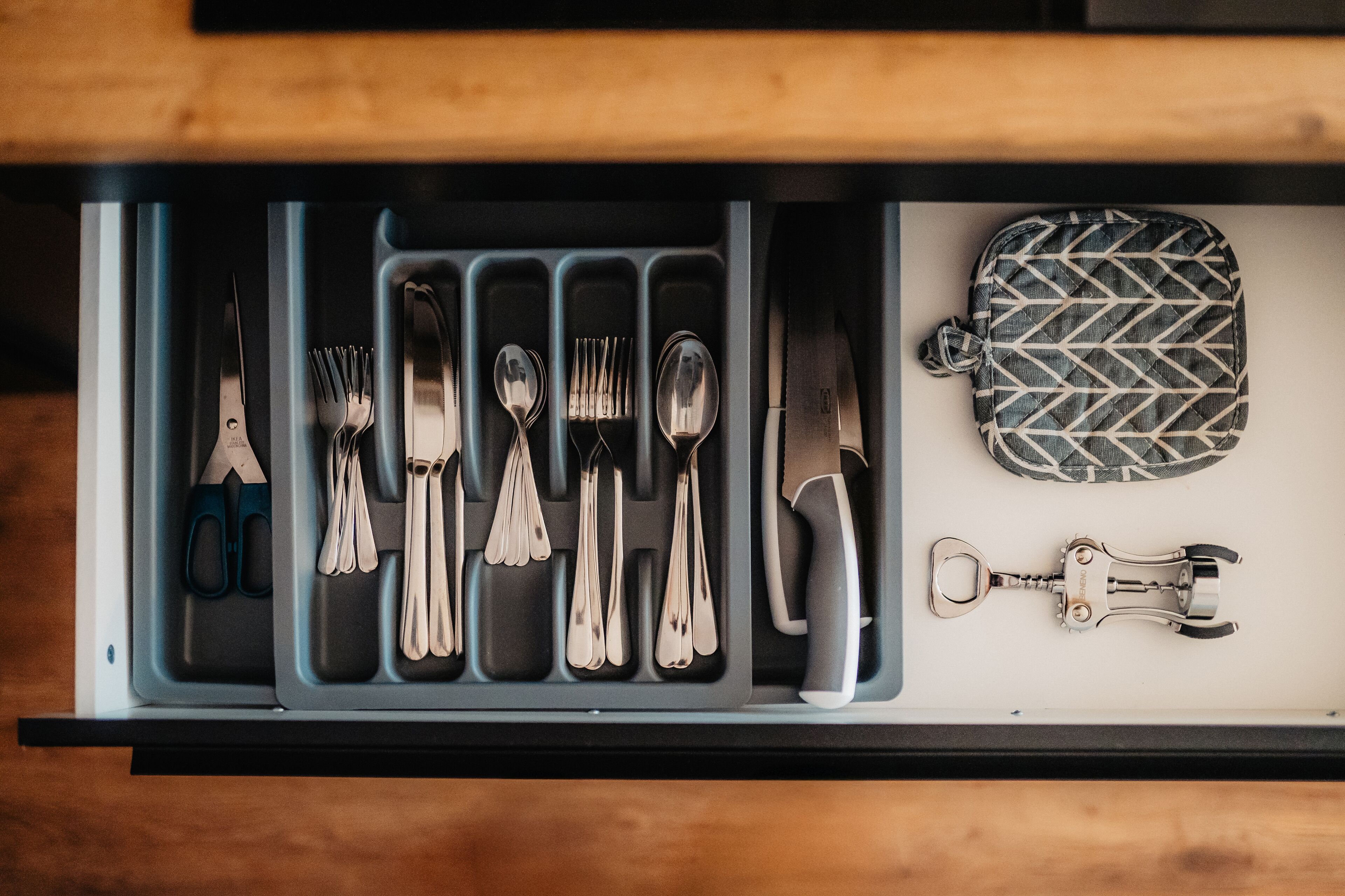 A drawer containing various utensils and a bottle opener.