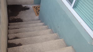 A concrete staircase leading to a door with a doormat that reads "The Home of the Sly Fox." - Beautiful Newly Renovated Basement Apartment (Ogden)