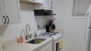 A kitchen with white cabinets, a gas stove, a sink, and a refrigerator. - Beautiful Newly Renovated Basement Apartment (Ogden)