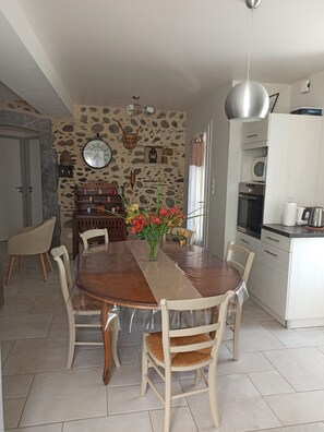 Un coin repas avec un mur en pierre, une table en bois et des chaises.