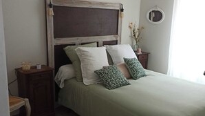 A neatly arranged bedroom with a bed, bedside tables, a hanging light fixture, and a mirror on the wall. - Gite Pouquette (Aramits)