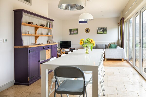 A modern kitchen with a dining table, chairs, and a TV.