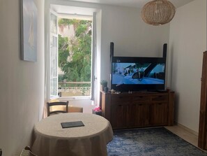 A room with a television mounted on the wall, a window with a view of greenery, and a roll of toilet paper on the floor. - heart of Cannes near all life of the city (Cannes)