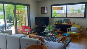 A modern living room with a sofa, TV, and a dining area with chairs and a table.