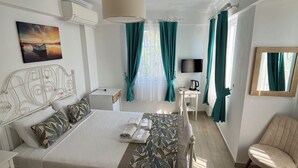 A hotel room with a bed, a desk, a chair, a TV, and a painting on the wall.