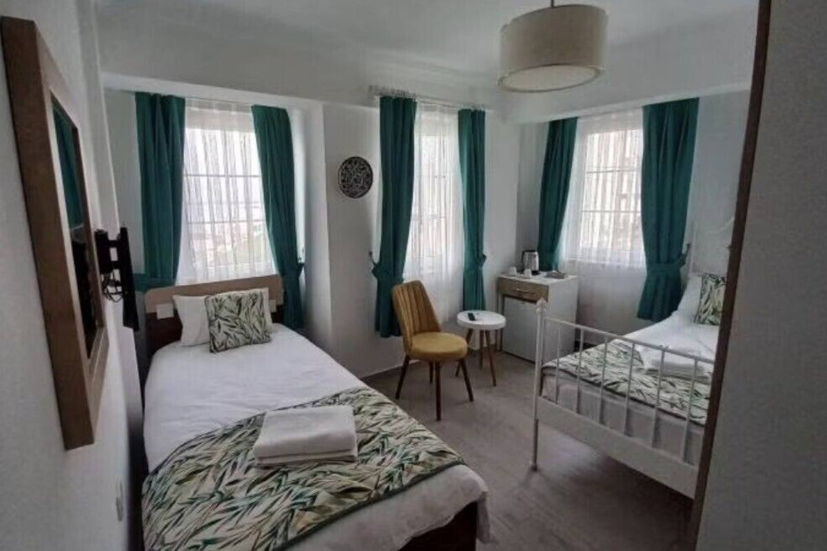 Une chambre à coucher avec un lit, une chaise, un bureau et une fenêtre avec des rideaux.