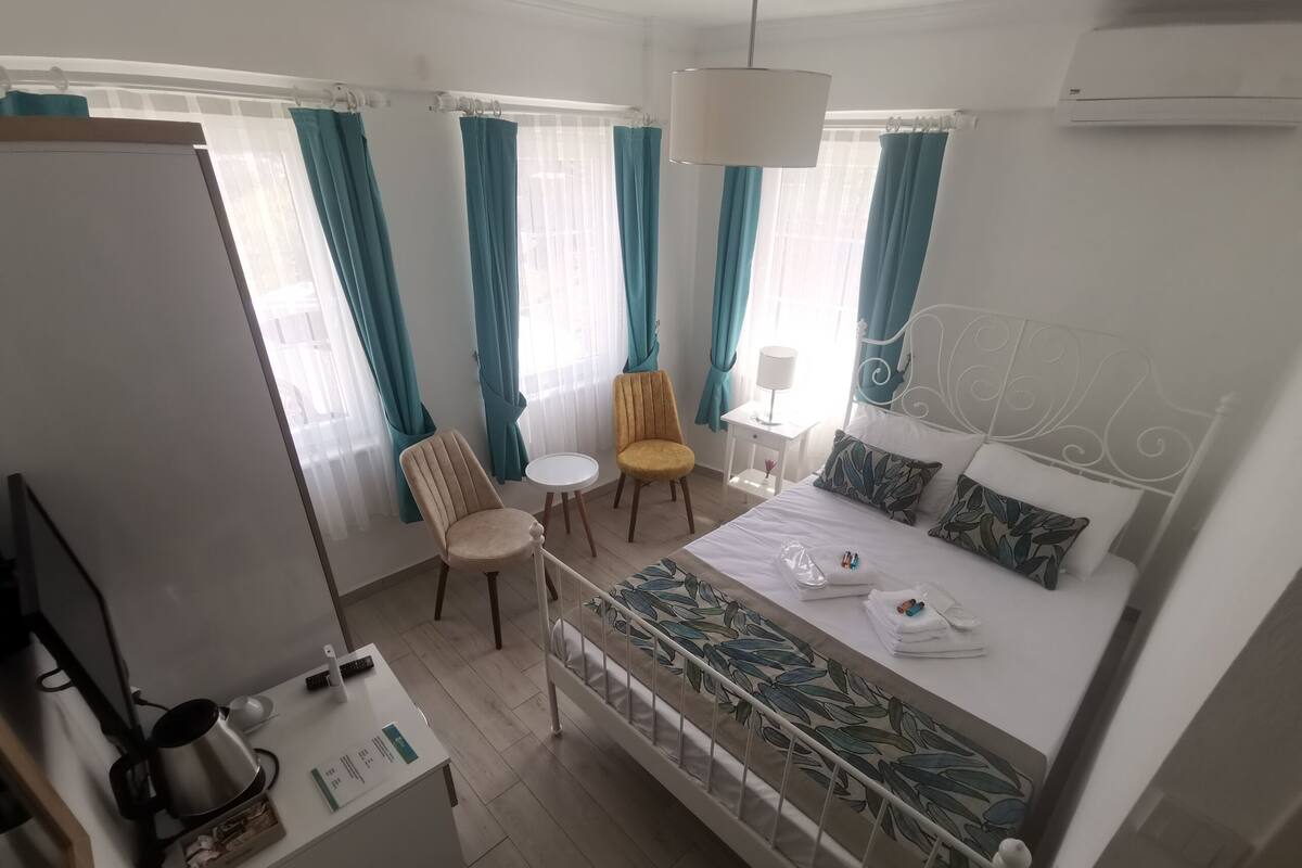 Une chambre d’hôtel avec un lit, un bureau doté d’une bouilloire, une chaise et une petite table.