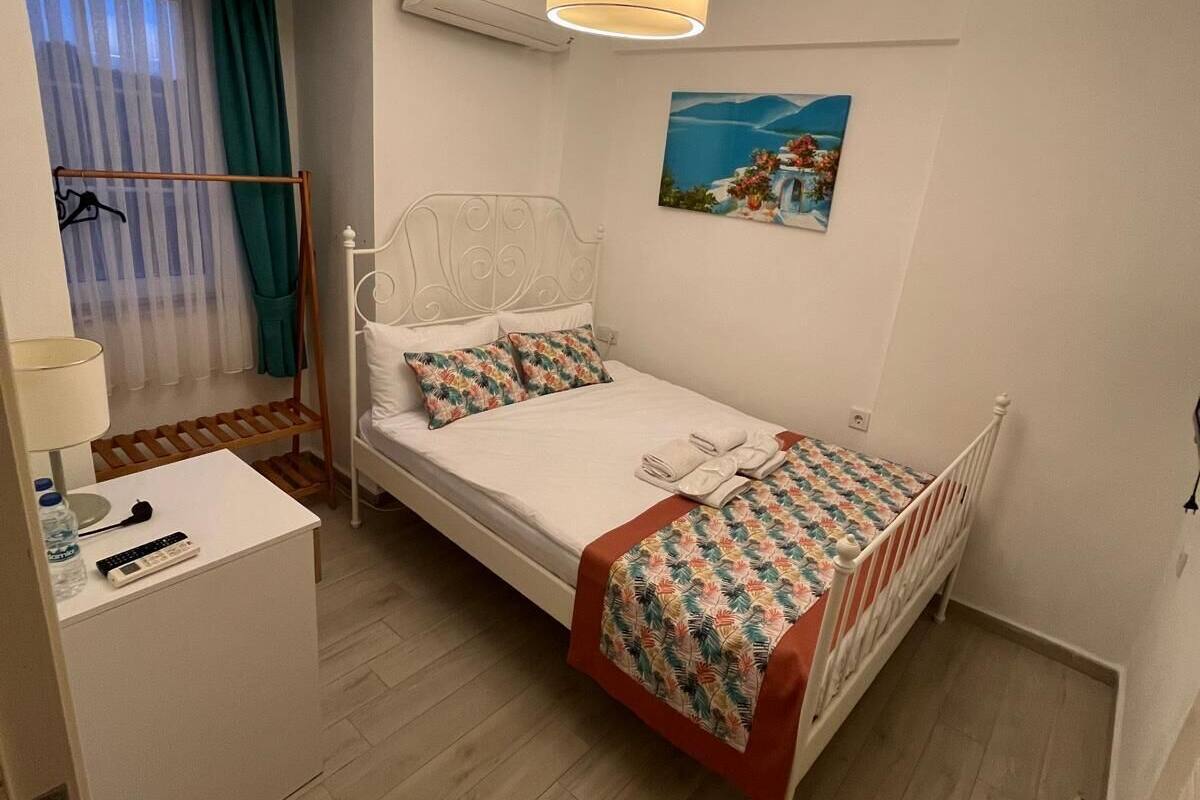 Une chambre bien rangée, avec un lit, une table de chevet et un tableau accroché au mur.