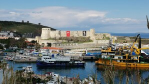 A coastal town with a historic stone fortress, a marina with boats, and a clear blue sky. - Valitsa Otel (Bozcaada)