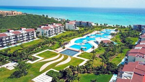 An aerial view of a resort with multiple swimming pools, lush greenery, and beachfront properties. - Mareazul Beach Condos Playa Del Carmen (Playa del Carmen)