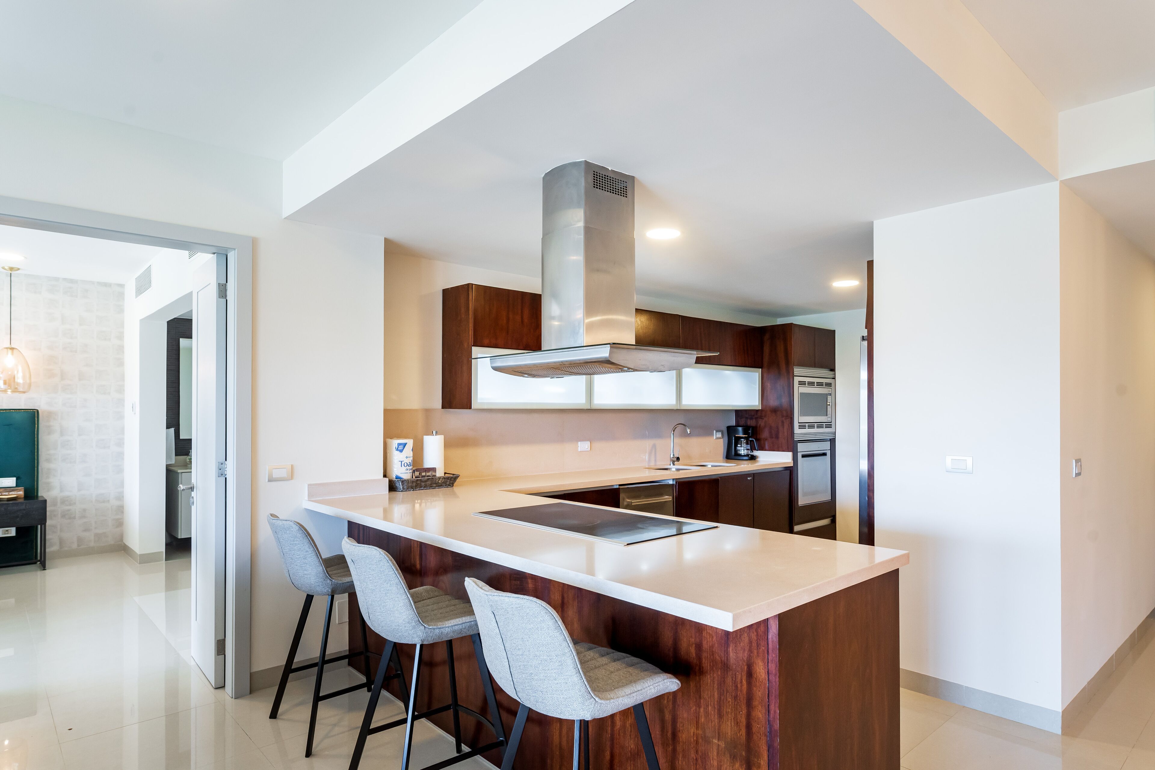 Una cocina moderna con una isla central, taburetes de bar y un horno empotrado.