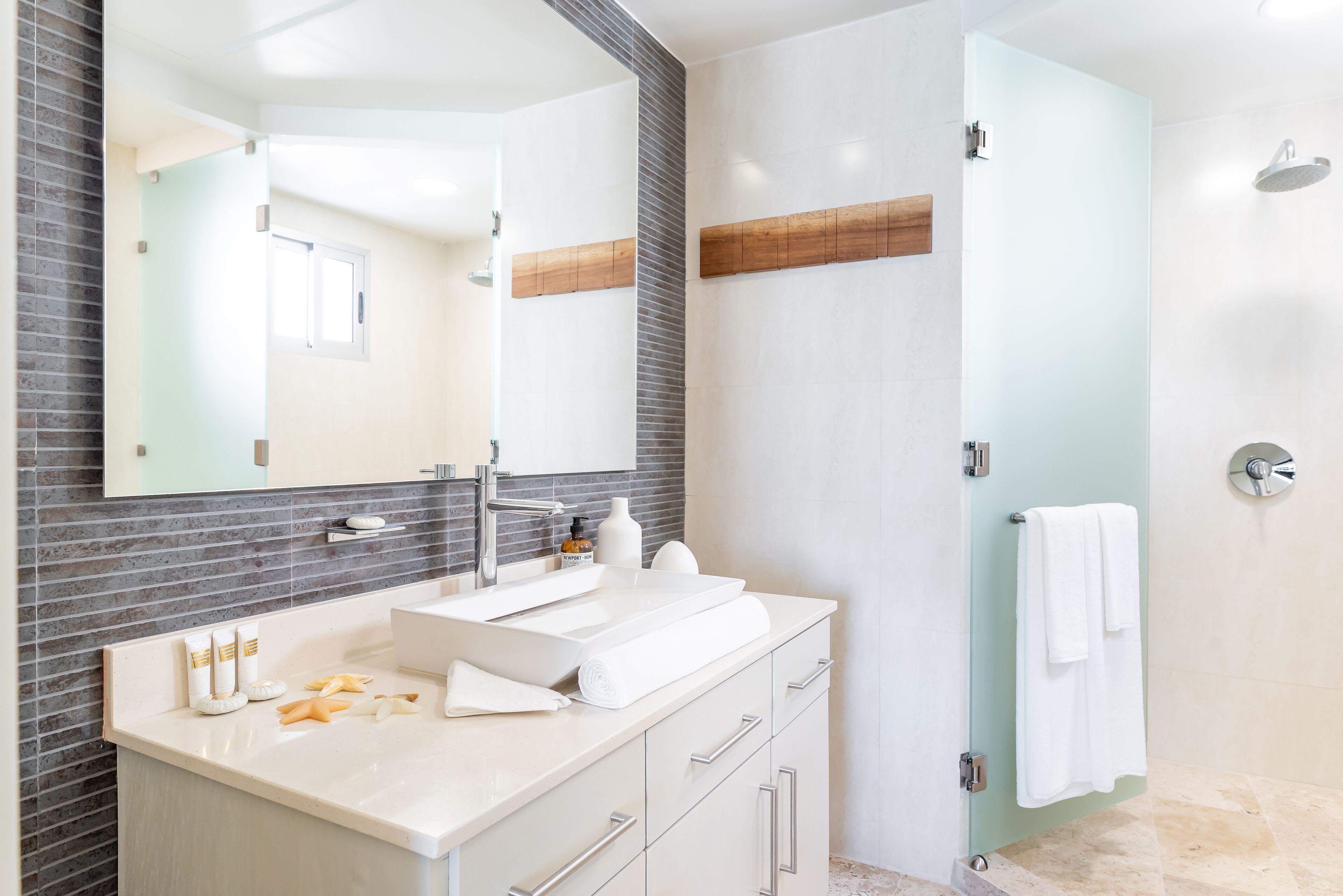 Un baño moderno con un espejo grande, un lavabo y una zona de ducha.