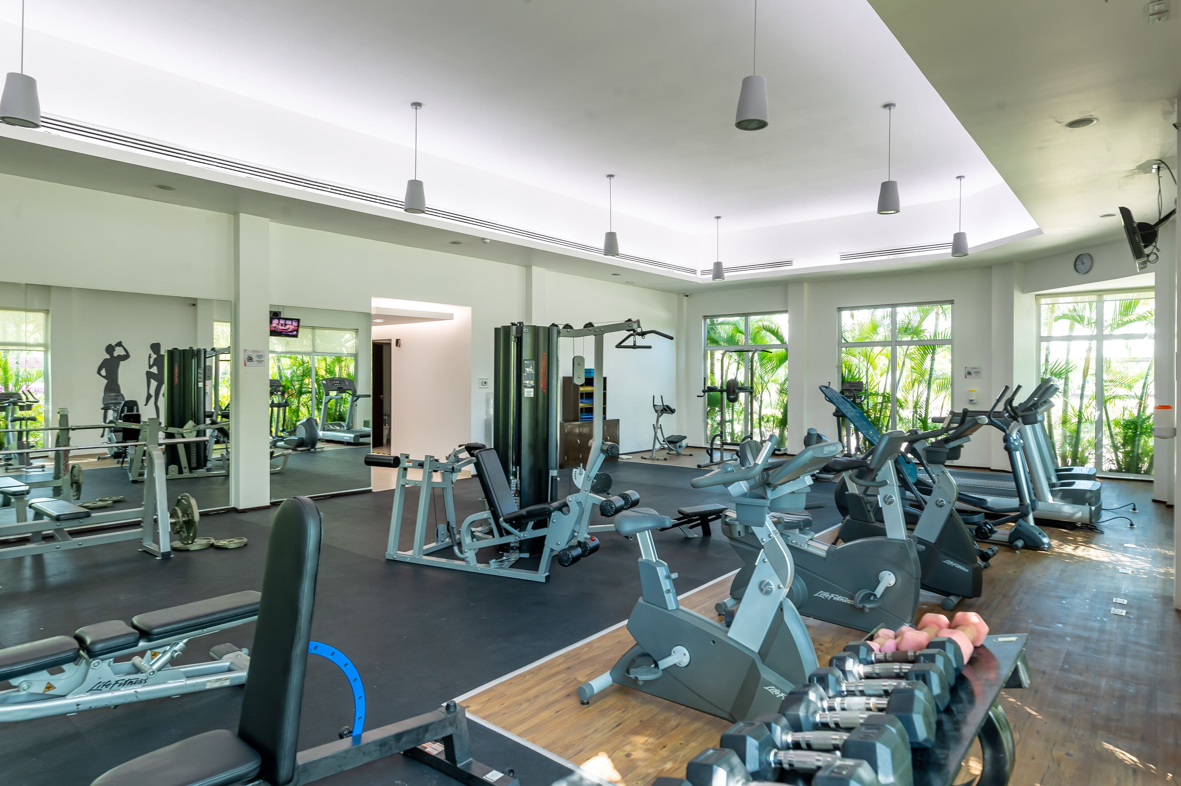 A spacious gym with various exercise equipment, large windows, and a clean, modern design.