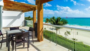 A balcony with a glass railing overlooking a beach with palm trees and a clear blue sky. - Mareazul Beach Condos Playa Del Carmen (Playa del Carmen)
