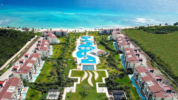 A resort with multiple buildings, a central pool area, and a beach view. - Mareazul Beach Condos Playa Del Carmen (Playa del Carmen)