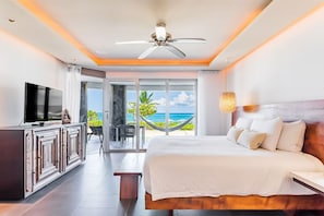 A hotel room with a bed, a TV, a desk, and a view of the ocean. - Mareazul Beach Condos Playa Del Carmen (Playa del Carmen)
