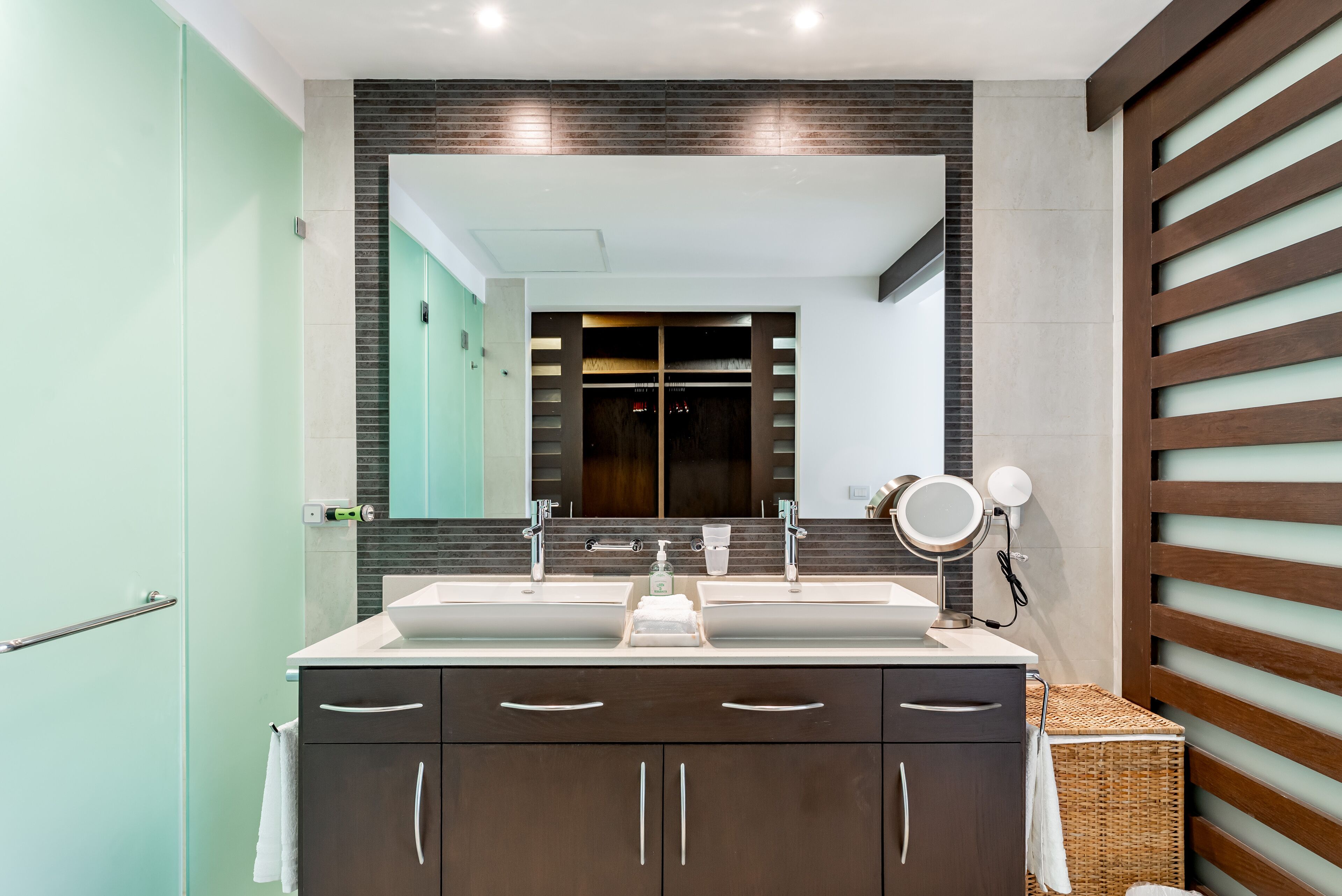 A modern bathroom with a dual sink vanity, a large mirror, and a wooden slatted wall design.