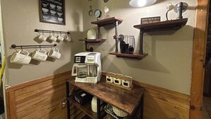 A coffee station with a coffee maker, mugs, and a tea station.