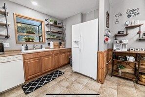 A modern kitchen with wooden cabinets, a built-in oven, a refrigerator, and a coffee station.