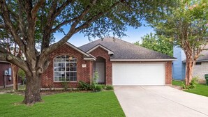A residential house with a brick facade, a garage, and a well-maintained lawn.