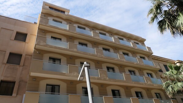 A multi-story building with balconies, a visible security camera, and a clear sky. - Rusadir (Melilla)